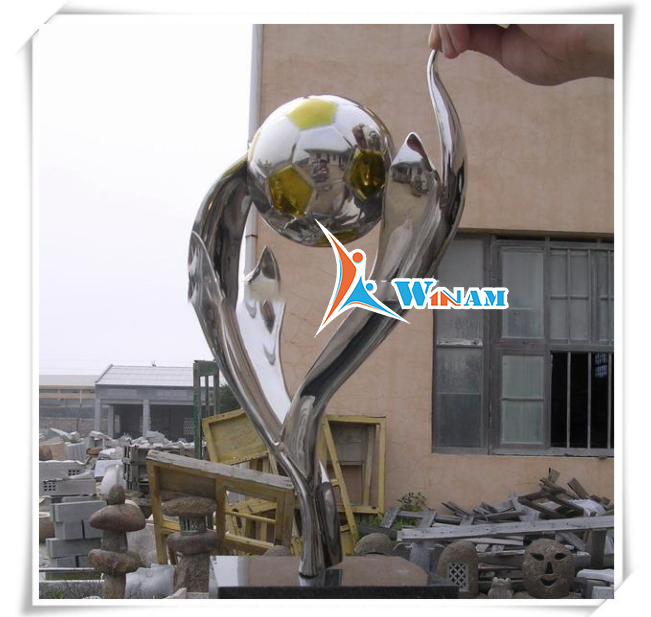 Hands hold football stainless steel sculpture for garden decor